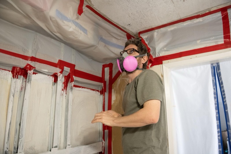 Emergency mold remediation crew in PPE responding to water-damaged home with industrial extraction equipment