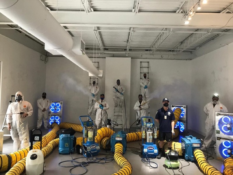 IICRC-certified mold remediation technician operating industrial dehumidifier and HEPA air scrubber in containment zone